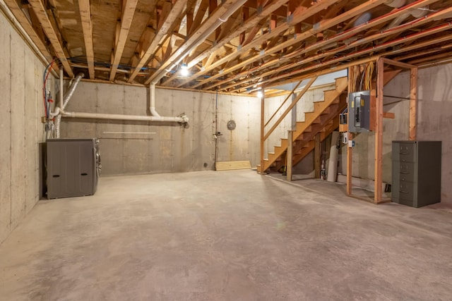 unfinished basement featuring stairs and electric panel
