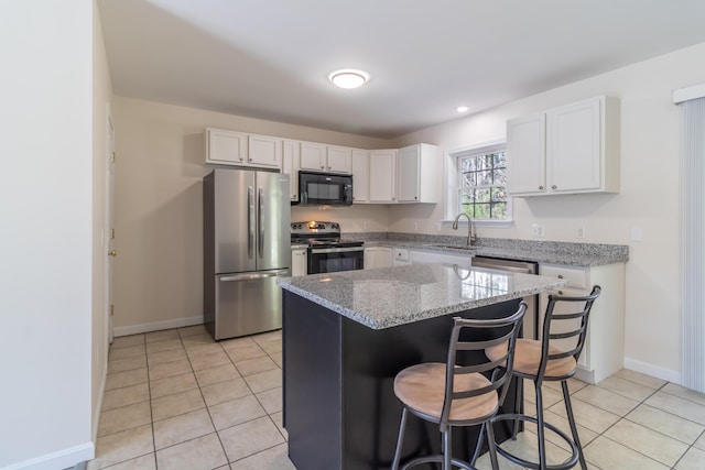 kitchen featuring light tile patterned flooring, appliances with stainless steel finishes, a sink, a center island, and white cabinetry