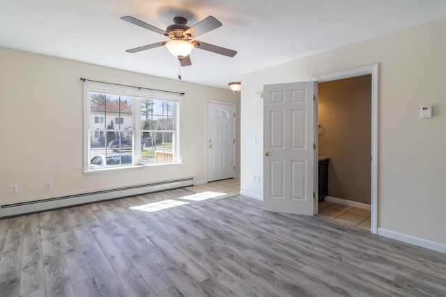 unfurnished bedroom with a ceiling fan, baseboards, a baseboard heating unit, and wood finished floors