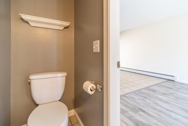 bathroom with baseboards, a baseboard heating unit, and toilet