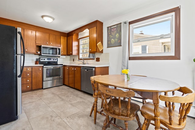 kitchen with brown cabinetry, decorative backsplash, appliances with stainless steel finishes, and light countertops