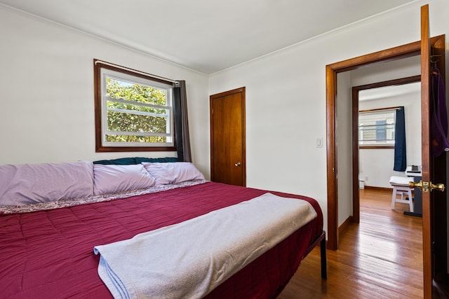 bedroom featuring baseboards, ornamental molding, wood finished floors, and a baseboard radiator