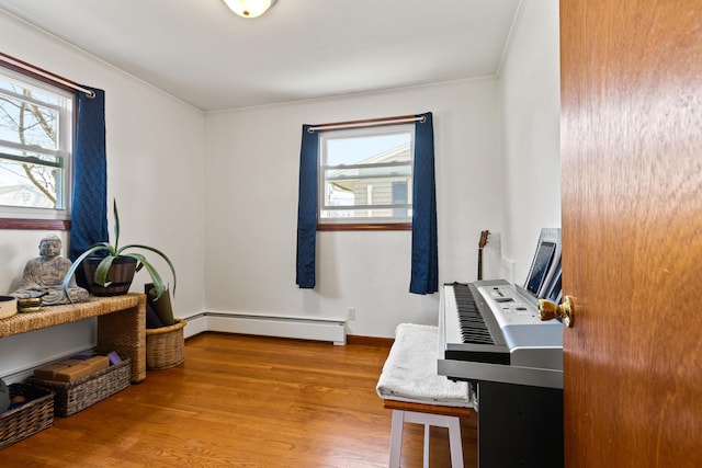 office featuring crown molding, baseboard heating, wood finished floors, and a wealth of natural light