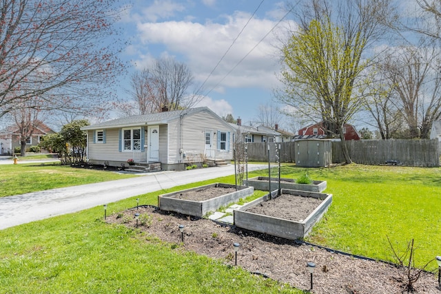 view of side of property with fence, a lawn, and a garden