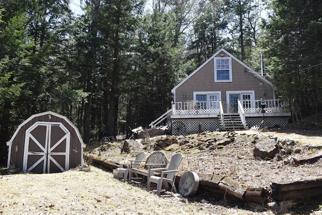 158 Old Stage Rd, Readfield, ME 04355 - back of house featuring a forest view, a wooden deck, an outdoor structure, and a storage unit