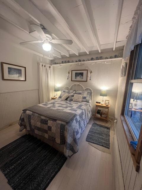 158 Old Stage Rd, Readfield, ME 04355 - bedroom featuring wood walls, wainscoting, wood finished floors, beamed ceiling, and a ceiling fan