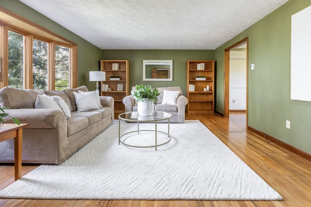 living room featuring a textured ceiling, baseboards, and wood finished floors