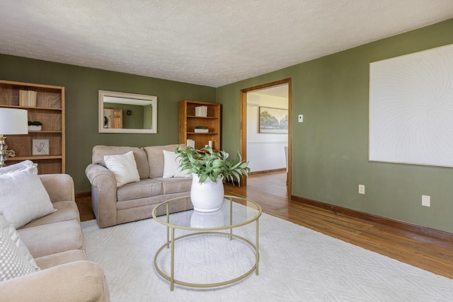 living area featuring baseboards, a textured ceiling, and wood finished floors