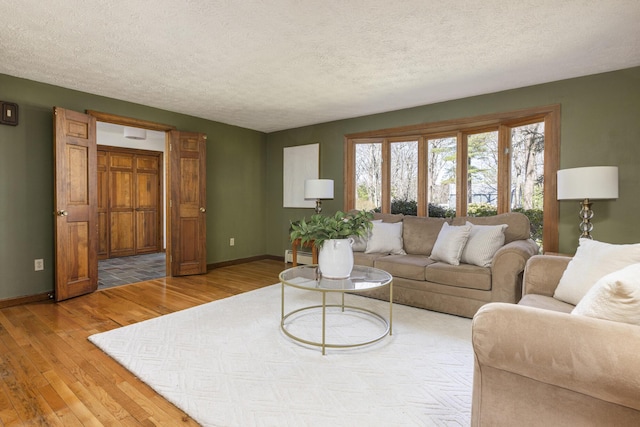 living room featuring baseboards, a textured ceiling, light wood finished floors, and a baseboard heating unit
