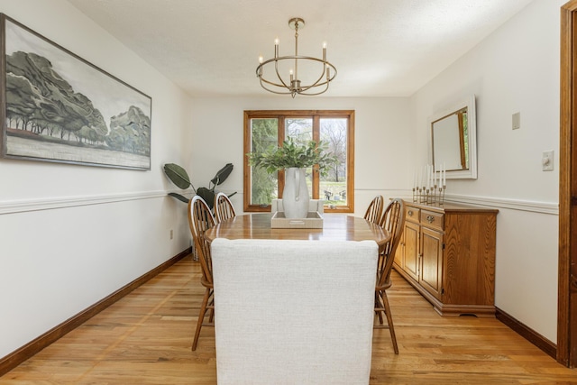 dining area featuring an inviting chandelier, baseboards, and light wood finished floors