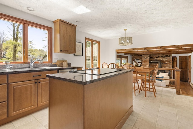 kitchen featuring a kitchen island, black electric cooktop, brown cabinets, light tile patterned floors, and a notable chandelier