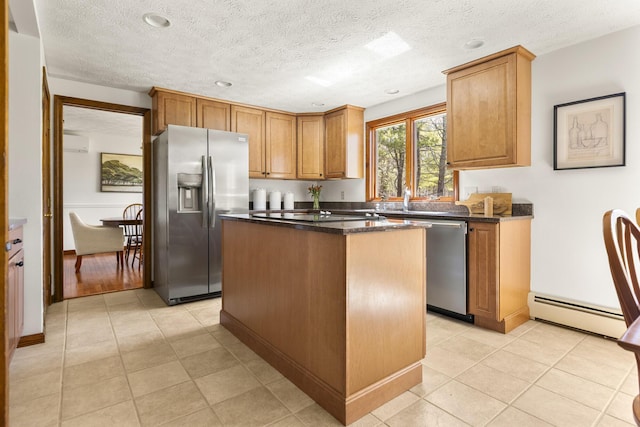 kitchen with a center island, dark stone counters, a wall mounted AC, a baseboard radiator, and appliances with stainless steel finishes