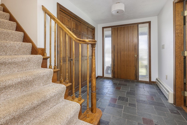 entrance foyer with stone tile flooring, a baseboard radiator, baseboards, and stairway