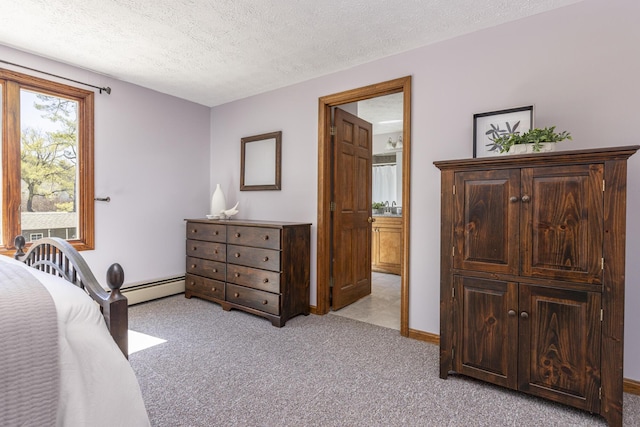 bedroom featuring a baseboard radiator, a textured ceiling, ensuite bath, and light carpet