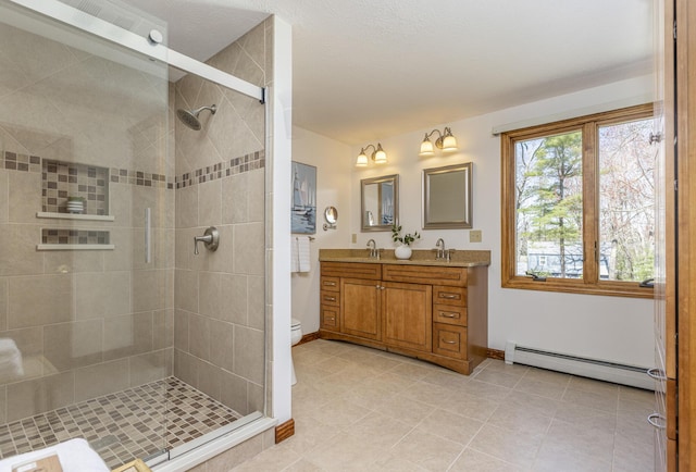 bathroom with double vanity, baseboards, a baseboard heating unit, and a stall shower