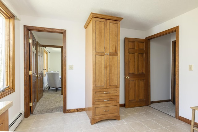 hall with baseboards, light tile patterned floors, and a baseboard radiator