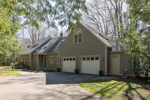 view of front of property featuring a garage, aphalt driveway, and a chimney