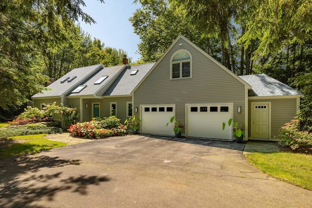 view of front of house featuring driveway, a chimney, roof with shingles, and a garage