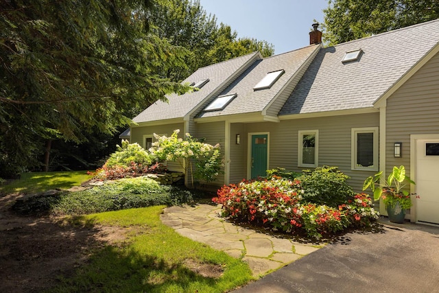 cape cod-style house featuring a chimney and roof with shingles