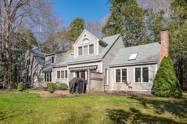 back of property featuring a patio, roof with shingles, a yard, and a chimney