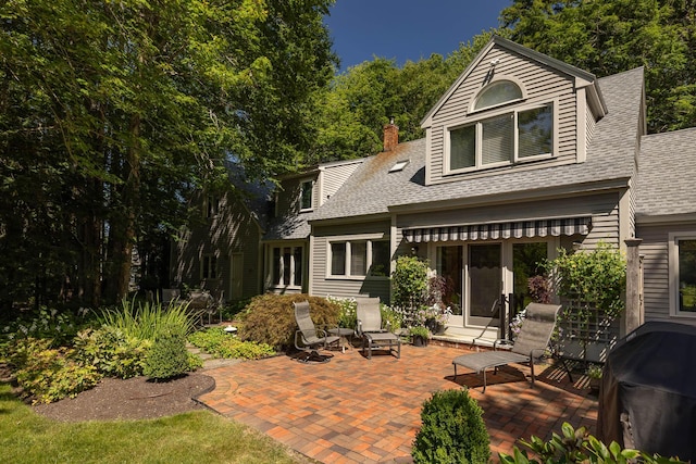 rear view of property featuring french doors, a shingled roof, a chimney, and a patio area