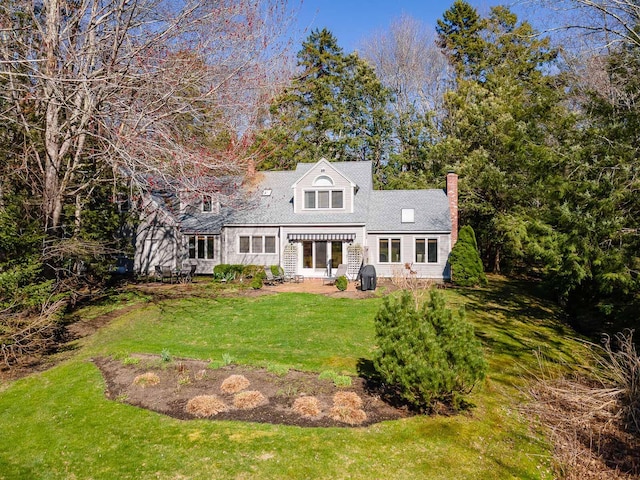 back of house featuring a chimney and a yard