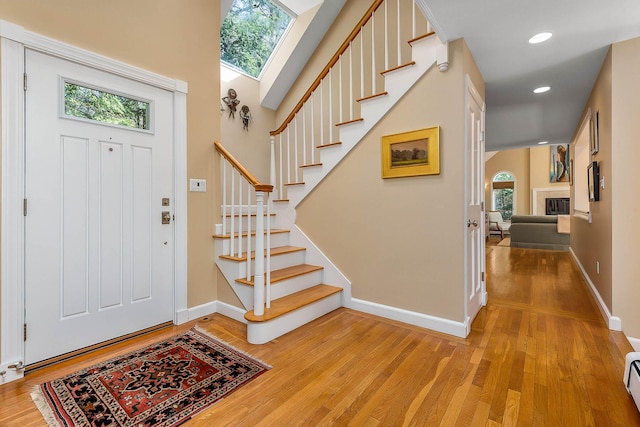 foyer with light wood-style floors, stairs, baseboards, and a wealth of natural light