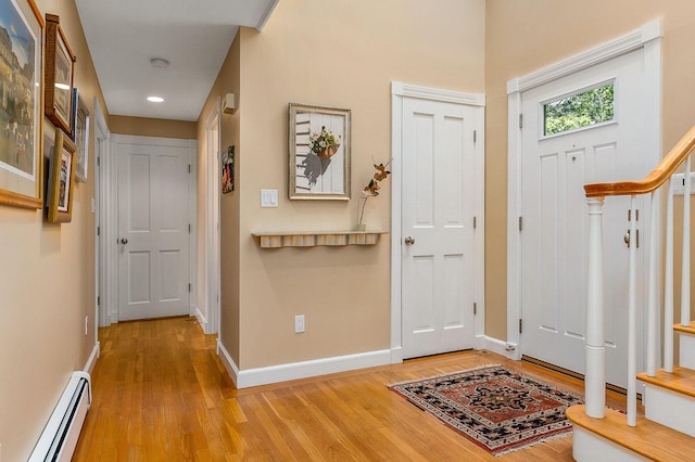 foyer featuring light wood finished floors, stairs, recessed lighting, baseboards, and a baseboard radiator