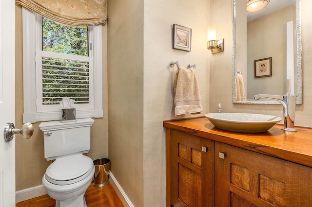 bathroom featuring toilet, baseboards, wood finished floors, and vanity