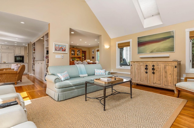 living room with light wood-type flooring, recessed lighting, high vaulted ceiling, and a skylight