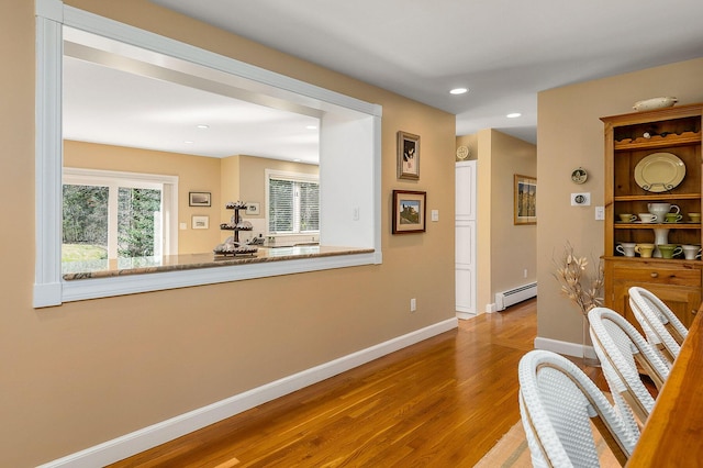 hall with baseboards, a baseboard radiator, recessed lighting, and wood finished floors