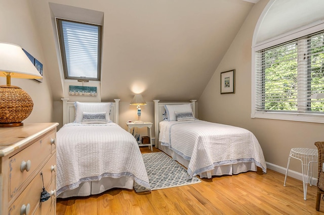 bedroom featuring light wood-style floors, baseboards, and lofted ceiling