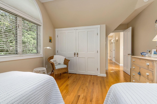 bedroom featuring light wood-style floors, baseboards, and vaulted ceiling