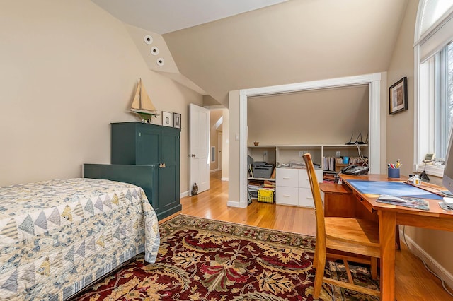 bedroom with lofted ceiling and light wood-style floors