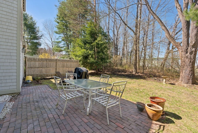 view of patio featuring grilling area, fence, and outdoor dining space