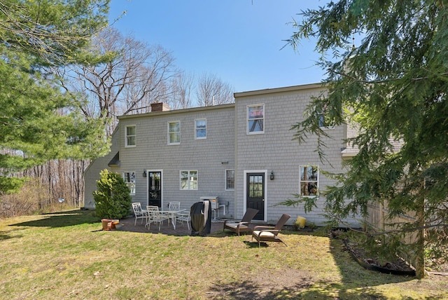 rear view of house featuring a yard, a chimney, and a patio area