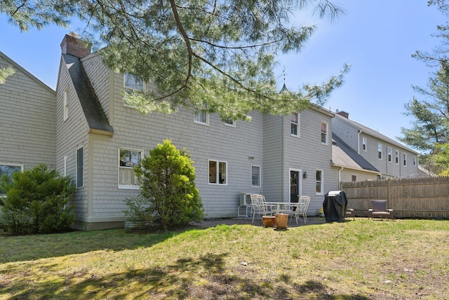 rear view of house featuring a lawn, fence, and a chimney