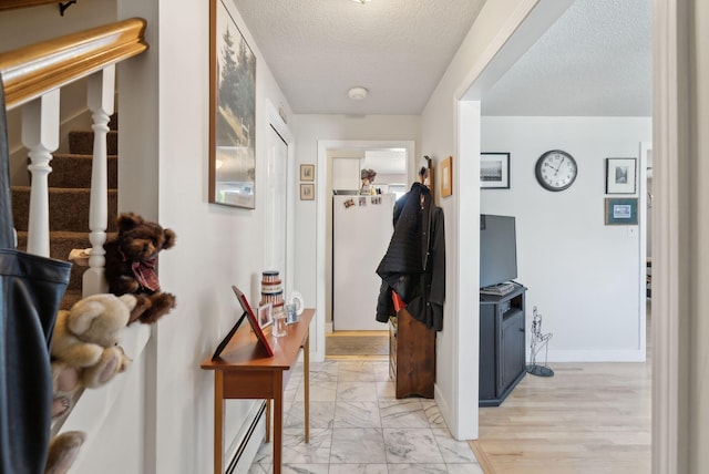 corridor featuring a textured ceiling, stairway, baseboards, a baseboard heating unit, and marble finish floor