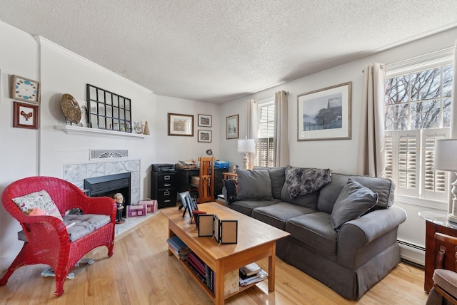 living room with wood finished floors, a textured ceiling, a baseboard heating unit, and a tile fireplace
