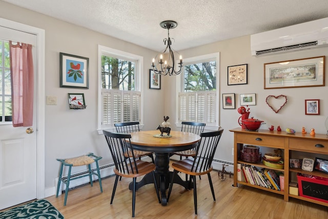 dining area with an inviting chandelier, light wood finished floors, a wall mounted air conditioner, a textured ceiling, and a baseboard radiator