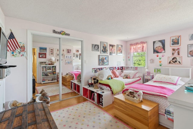 bedroom featuring a closet, a textured ceiling, and wood finished floors