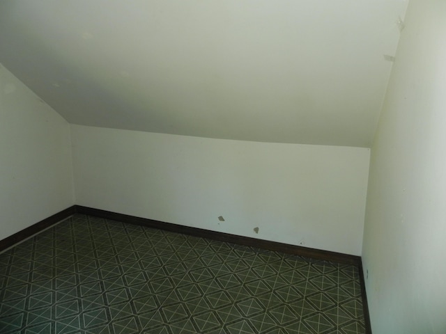 additional living space with tile patterned floors, baseboards, and vaulted ceiling