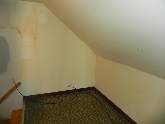additional living space with baseboards and lofted ceiling