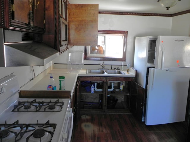 kitchen with a sink, dark wood-style floors, white appliances, and light countertops