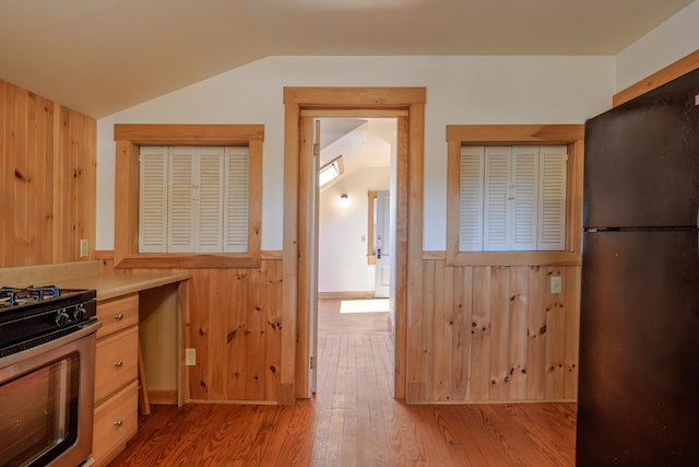 6 Sea St, Northeast Harbor, Mount Desert, ME 04662 - kitchen featuring freestanding refrigerator, lofted ceiling, stainless steel range with gas cooktop, wooden walls, and a wainscoted wall