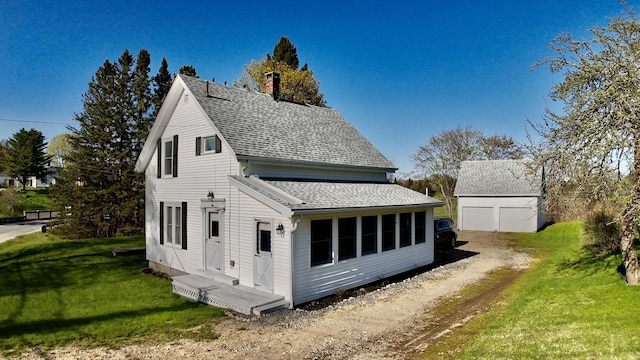 30 Mill St, Harrington, ME 04643 - view of side of home featuring a chimney, a detached garage, roof with shingles, a yard, and an outbuilding