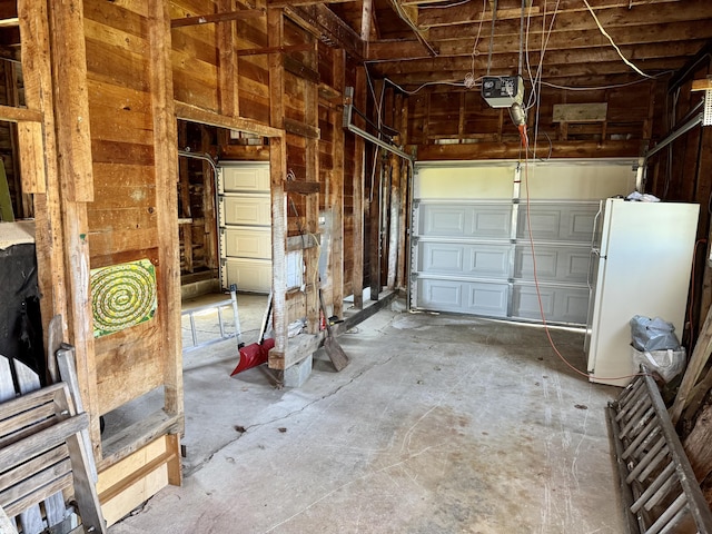 30 Mill St, Harrington, ME 04643 - garage with freestanding refrigerator, a garage door opener, and wooden walls