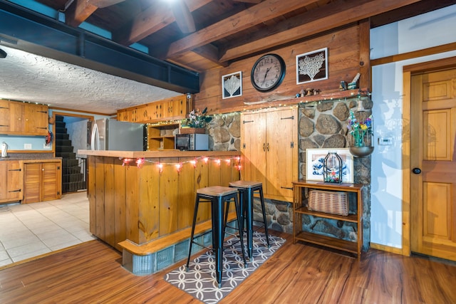 kitchen with wood walls, light wood finished floors, brown cabinets, and freestanding refrigerator