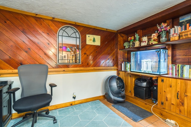 interior space with a textured ceiling, baseboards, and wood walls