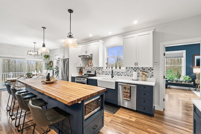 29 Hawks Nest Ln, Wells, ME 04090 - kitchen featuring stainless steel appliances, wood counters, a sink, backsplash, and a breakfast bar area